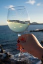 Tasting of glass of cold white wine on outdoor terrace with sea Royalty Free Stock Photo
