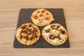 Tasting of Spanish-style pizzas with mushrooms, blood sausage, cheese, serrano ham, onion, chicken and pine nuts on a black slate