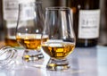 Tasting of whiskey, tulip-shaped tasting glasses with dram of Scotch single malt or blended whisky on white table