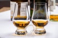 Tasting of whiskey, tulip-shaped tasting glasses with dram of Scotch single malt or blended whisky on white table