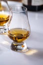 Tasting of whiskey, tulip-shaped tasting glasses with dram of Scotch single malt or blended whisky on white table