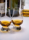 Tasting of whiskey, tulip-shaped tasting glasses with dram of Scotch single malt or blended whisky on white table
