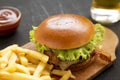 Tasty amburger, french fries, sauce and glass of cold beer on a black background, side view. Close-up Royalty Free Stock Photo