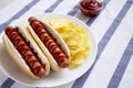 Tasty American Hot Dog with Potato Chips on a white plate, side view. Space for text Royalty Free Stock Photo