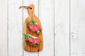 Tasty appetizer of thinly sliced spicy salami on bread with cheese and herbs on a cutting board with copy space Royalty Free Stock Photo