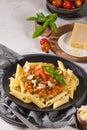 Tasty appetizing classic italian penne pasta with vegetarian lentil bolognese sauce, cheese parmesan and basil on plate on light Royalty Free Stock Photo