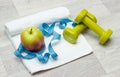 Tasty apple, measure tape and weights on towel Royalty Free Stock Photo