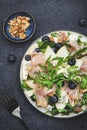Tasty arugula salad with sweet pears, blueberries, roquefort cheese, smoked pork ham and crunchy walnuts. Black kitchen table Royalty Free Stock Photo