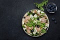 Tasty arugula salad with sweet pears, blueberries, roquefort cheese, smoked pork ham and crunchy walnuts. Black kitchen table Royalty Free Stock Photo