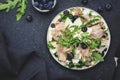 Tasty arugula salad with sweet pears, blueberries, roquefort cheese, smoked pork ham and crunchy walnuts. Black kitchen table Royalty Free Stock Photo