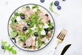Tasty arugula salad with sweet pears, blueberries, roquefort cheese, smoked pork ham and crunchy walnuts. White kitchen table Royalty Free Stock Photo