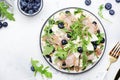 Tasty arugula salad with sweet pears, blueberries, roquefort cheese, smoked pork ham and crunchy walnuts. White kitchen table Royalty Free Stock Photo