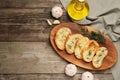 Tasty baguette with garlic, dill and oil on wooden table, flat lay. Space for text