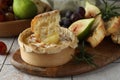 Tasty baked brie cheese, bread and other products on light tiled table Royalty Free Stock Photo