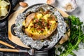 Tasty baked potato topped with cheddar cheese and chives. White background. Top view