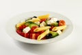 Tasty beautiful greek traditional greek or italian salad with vegetables and pasta on plate. Bright Background. Royalty Free Stock Photo