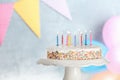 Tasty birthday cake with burning candles on stand against blurred background Royalty Free Stock Photo