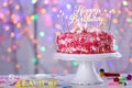 Tasty birthday cake with burning candles on table against defocused lights Royalty Free Stock Photo