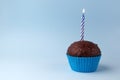 Tasty birthday cupcake with candle, on blue background, with free space Royalty Free Stock Photo