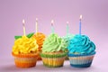 Tasty birthday cupcakes with burning candles on color background Royalty Free Stock Photo