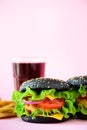 Tasty black burgers or hamburger served with french fries on pink background. Copy space. Fast food for breakfast, lunch Royalty Free Stock Photo