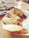 Tasty bread with garlic, cheese and herbs in white dish on table.