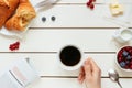 Tasty breakfast with coffee, berries, croissant on the white wooden table, top view