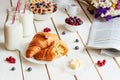 Tasty breakfast with croissant, oat flakes, berries and milk on the white wooden table Royalty Free Stock Photo