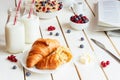 Tasty breakfast with croissant, oat flakes, berries and milk on the white wooden table Royalty Free Stock Photo