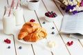 Tasty breakfast with croissant, oat flakes, berries and milk on the white wooden table Royalty Free Stock Photo