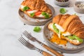 Tasty breakfast with croissant sandwiches with poached egg, avocado, soft cheese, mozzarella and tomato in a plate Royalty Free Stock Photo