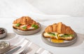 Tasty breakfast with croissant sandwiches with poached egg, avocado, soft cheese, mozzarella and tomato Royalty Free Stock Photo