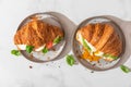 Tasty breakfast with croissant sandwiches with poached egg, avocado, soft cheese, mozzarella and tomato. top view Royalty Free Stock Photo