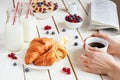 Tasty breakfast with cup of coffee, croissants, oat flakes, berries and milk on the white wooden table Royalty Free Stock Photo