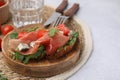 Tasty bruschetta with prosciutto, arugula, cheese and tomato served on light grey table, closeup Royalty Free Stock Photo