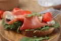 Tasty bruschetta with prosciutto, arugula, cheese and tomato on wooden board, closeup Royalty Free Stock Photo