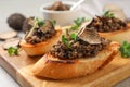 Tasty bruschettas with truffle paste on wooden board, closeup