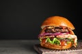 Tasty burger with bacon on table against black. Space for text Royalty Free Stock Photo