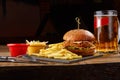 Tasty burger, french fries with sauce and glass of beer on black board Royalty Free Stock Photo