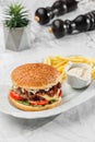 Tasty burger with french fries and sauce at the white plate on light marble background. Healthy sea food, hard light, restaurant Royalty Free Stock Photo