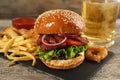 Tasty burger with French fries served on wooden table, closeup. Fast food Royalty Free Stock Photo