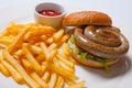 Tasty burger with fried potatoes and sausage, on white plate Royalty Free Stock Photo