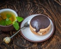 Tasty bushe cake with green tea with mint sprigs, teaspoon teaspoons on old wooden chair