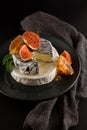 Tasty camembert with fresh figs and honey with honeycombs, decorated on a plate on dark background
