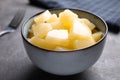 Tasty canned pineapple in bowl on table, closeup