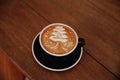 Tasty cappuccino with Christmas tree latte art on wooden brown background