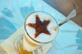 A tasty cappuccino drink in a large glass on the table. A chocolate star is on top of a cappuccino