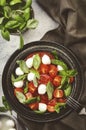 Tasty caprese salad with ripe red tomatoes and mozzarella cheese with fresh green basil leaves. Italian food. Top view Royalty Free Stock Photo