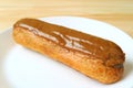 Tasty Caramel Eclair on a White Plate with Copy Space Royalty Free Stock Photo