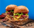 Tasty cheeseburgers on wooden tray close-up. Blue background